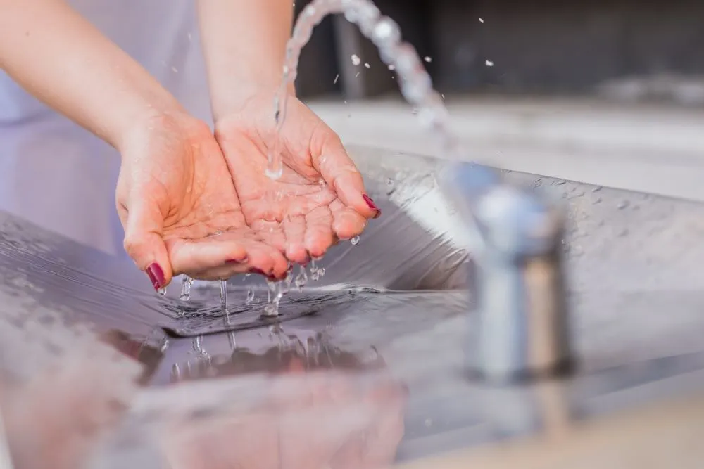 Fontaine à eau intégrée dans des toilettes publiques, utilisée pour le lavage des mains.