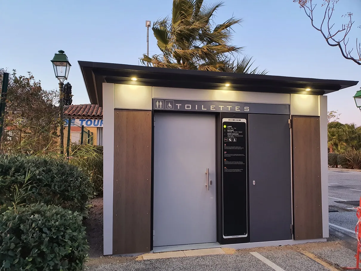 Sanitaires publics accessibles PMR avec signalétique toilettes, installés en extérieur dans un espace paysager