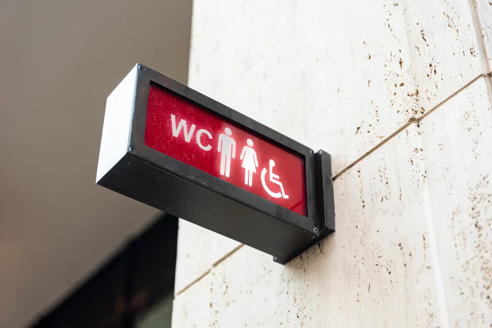 Panneau de signalétique WC lumineux indiquant toilettes hommes, femmes et accès PMR fixé au mur