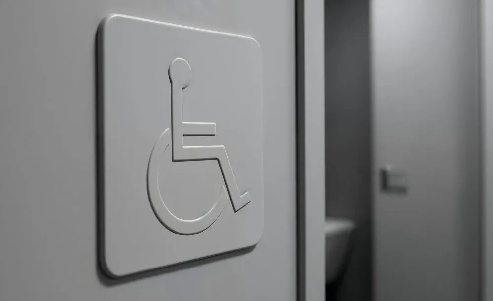 Porte d’un sanitaire public accessible avec pictogramme PMR menant à un WC adapté aux personnes à mobilité réduite